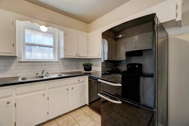 kitchen featuring dishwashing machine, dark countertops, a sink, and decorative backsplash