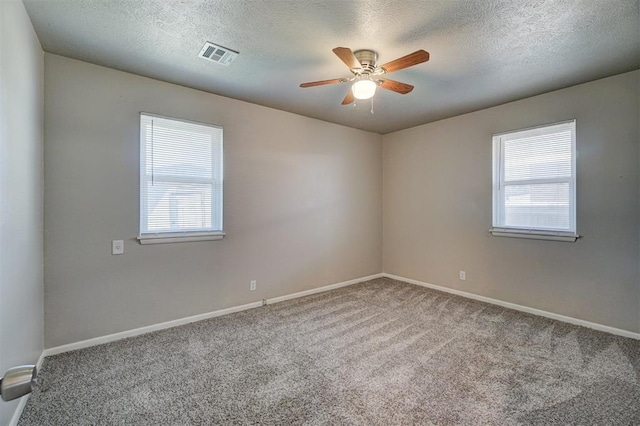 carpeted spare room with a wealth of natural light, visible vents, and baseboards