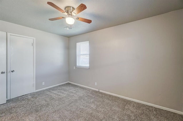 spare room with a textured ceiling, carpet floors, and baseboards