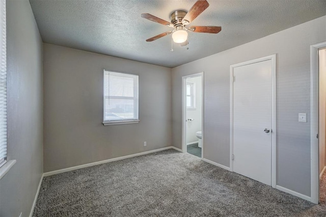 unfurnished bedroom with carpet floors, connected bathroom, a textured ceiling, and baseboards