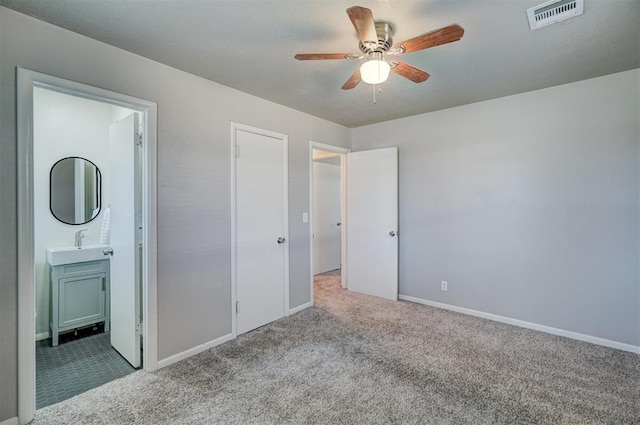 unfurnished bedroom featuring baseboards, visible vents, connected bathroom, carpet flooring, and a sink