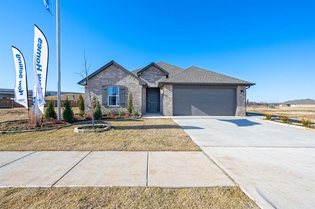 ranch-style home with a garage, concrete driveway, brick siding, and roof with shingles