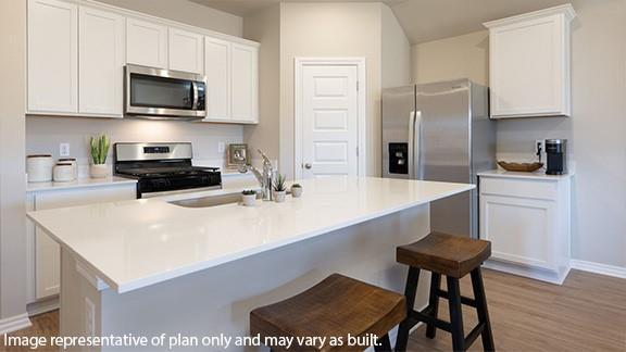 kitchen with a kitchen island with sink, a sink, white cabinetry, light countertops, and appliances with stainless steel finishes