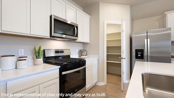 kitchen featuring stainless steel appliances, light countertops, and white cabinets