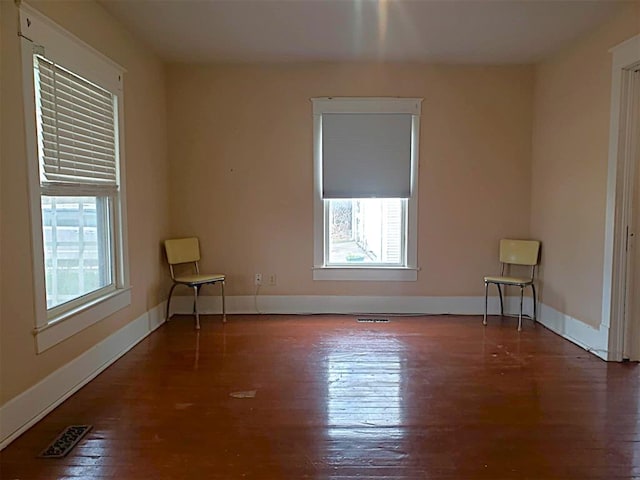 spare room with visible vents, baseboards, and wood finished floors