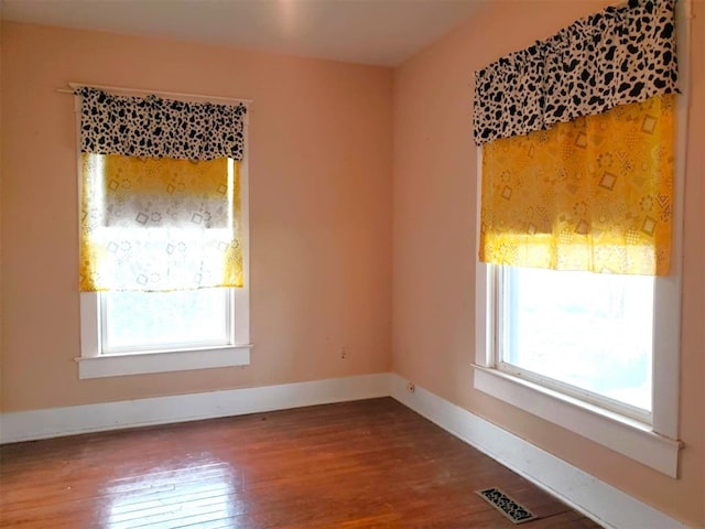 spare room featuring visible vents, baseboards, and wood finished floors