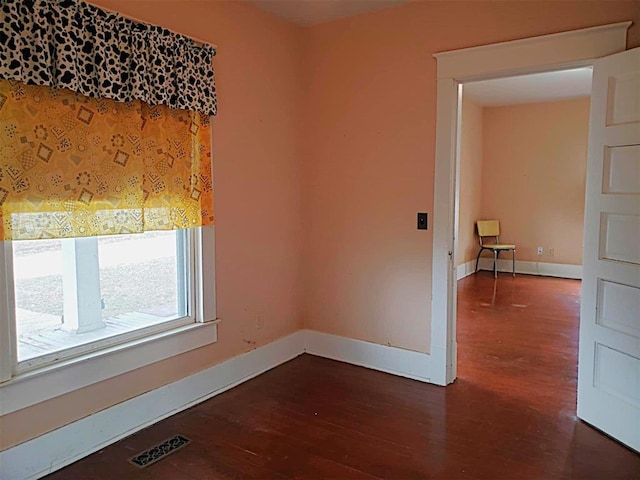 unfurnished room featuring visible vents, baseboards, and wood finished floors