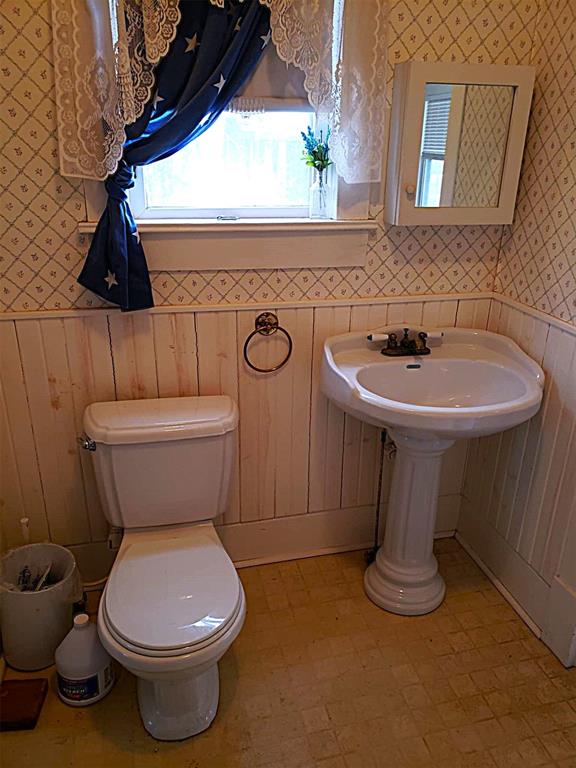 bathroom with tile patterned floors, a wainscoted wall, toilet, and wallpapered walls