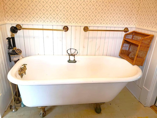 full bath with wainscoting, a freestanding tub, and wallpapered walls