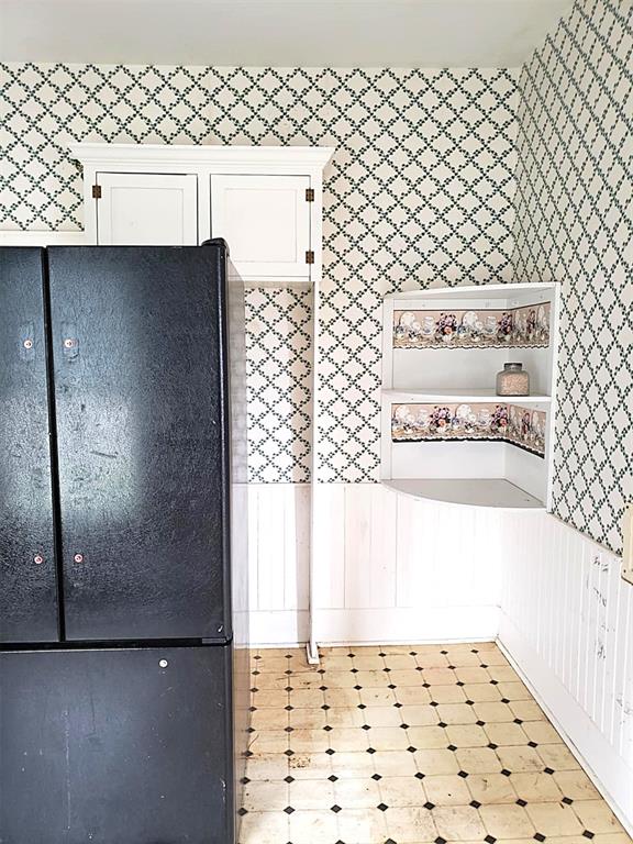 kitchen featuring light floors, freestanding refrigerator, and white cabinets