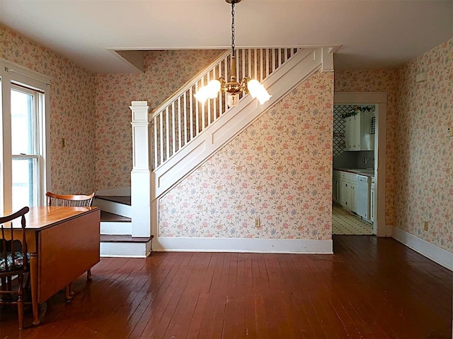 interior space featuring baseboards, hardwood / wood-style floors, an inviting chandelier, and wallpapered walls