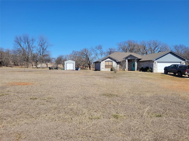 view of yard featuring a garage, a storage unit, and an outbuilding