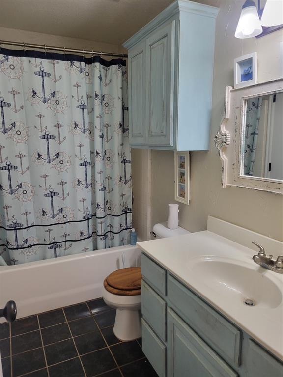 bathroom featuring shower / bath combo with shower curtain, vanity, toilet, and tile patterned floors