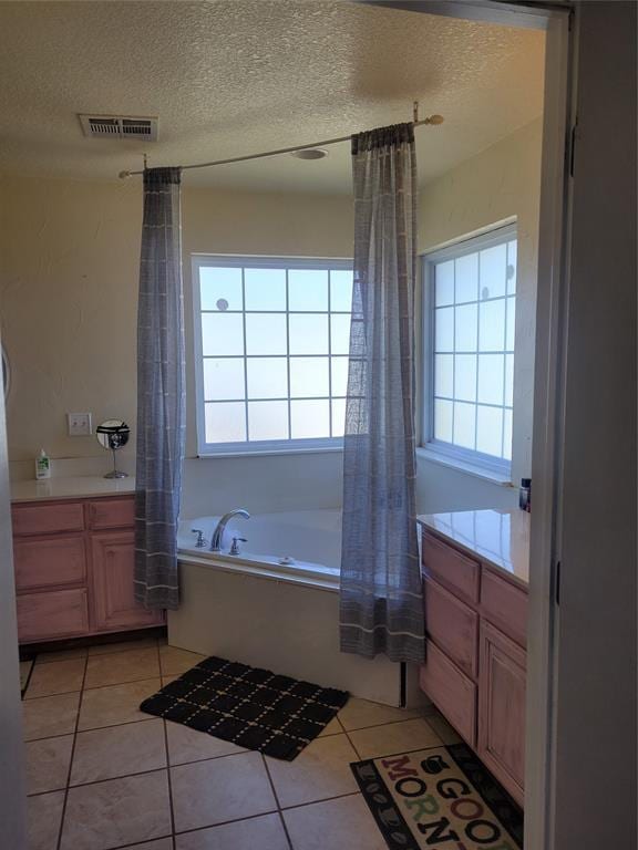 full bath featuring a textured ceiling, vanity, tile patterned flooring, and visible vents