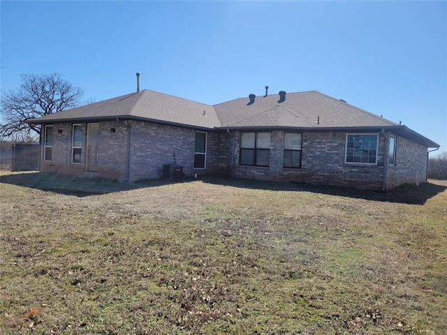 back of property with central air condition unit, brick siding, and a yard