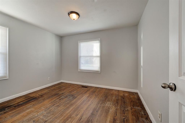 spare room with visible vents, baseboards, and wood finished floors