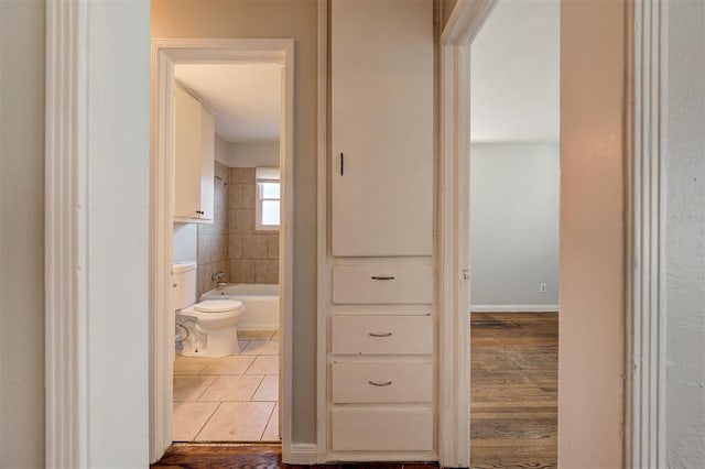 corridor with baseboards and tile patterned floors