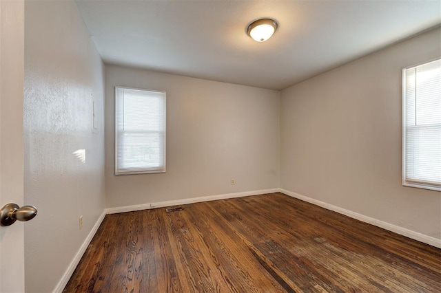 empty room with baseboards and dark wood finished floors