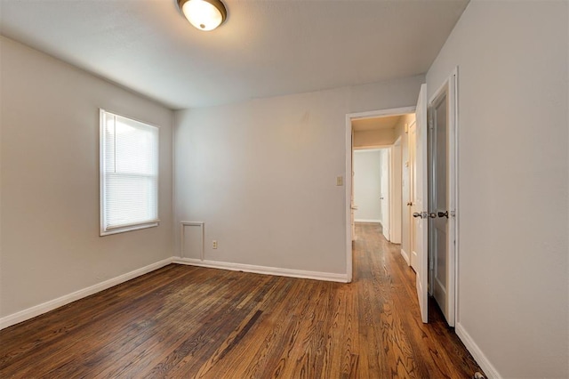 empty room featuring dark wood-style floors and baseboards