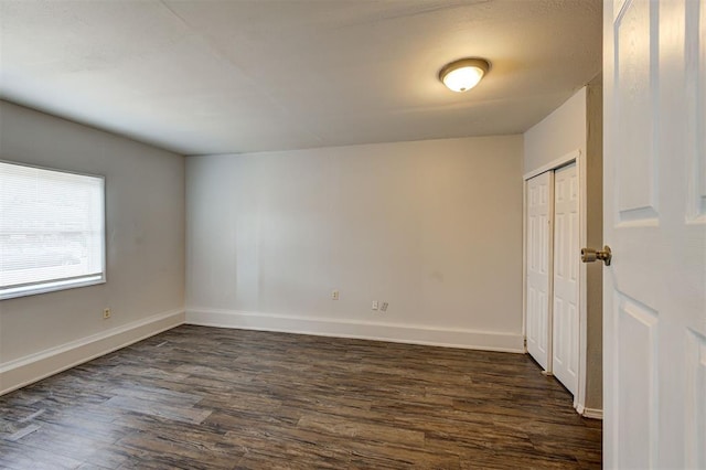 spare room featuring dark wood-style floors and baseboards