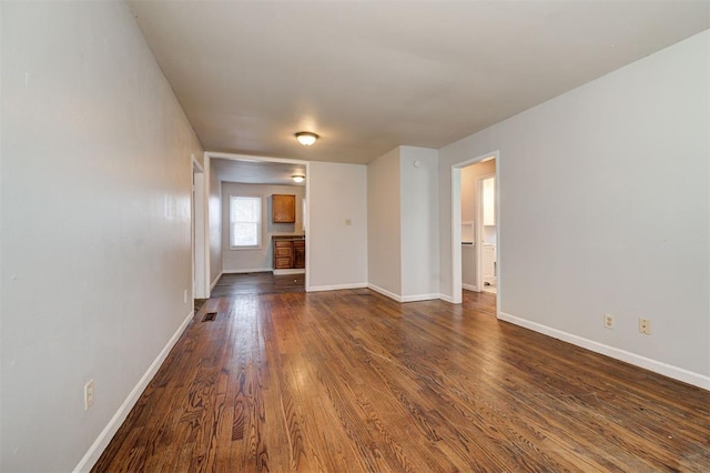 spare room with dark wood-style floors, visible vents, and baseboards