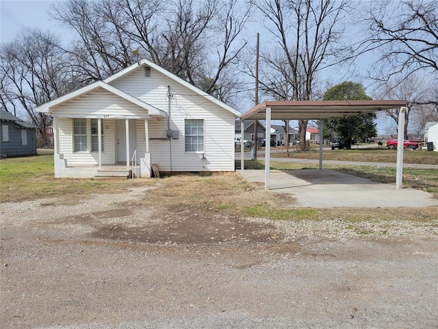 bungalow-style house featuring driveway, a porch, and a detached carport