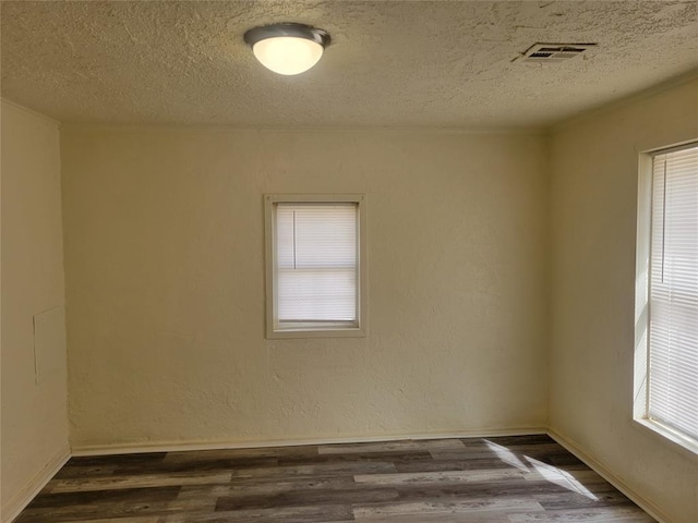 unfurnished room with a textured ceiling, a textured wall, dark wood finished floors, and visible vents