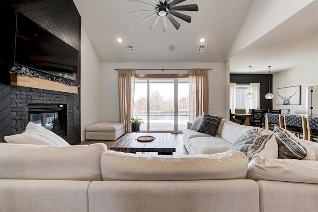 living room with vaulted ceiling, a fireplace, visible vents, and recessed lighting