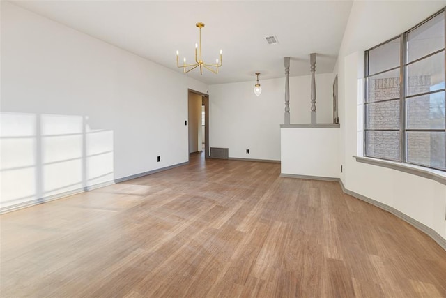 empty room with baseboards, light wood finished floors, visible vents, and a notable chandelier