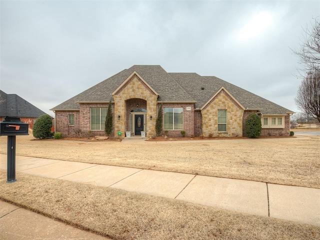 view of front of home featuring brick siding and roof with shingles