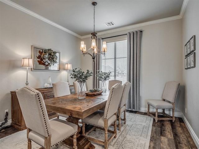 dining area with wood finished floors, visible vents, baseboards, ornamental molding, and an inviting chandelier