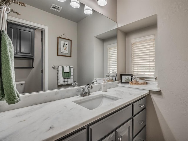 bathroom featuring toilet, vanity, and visible vents