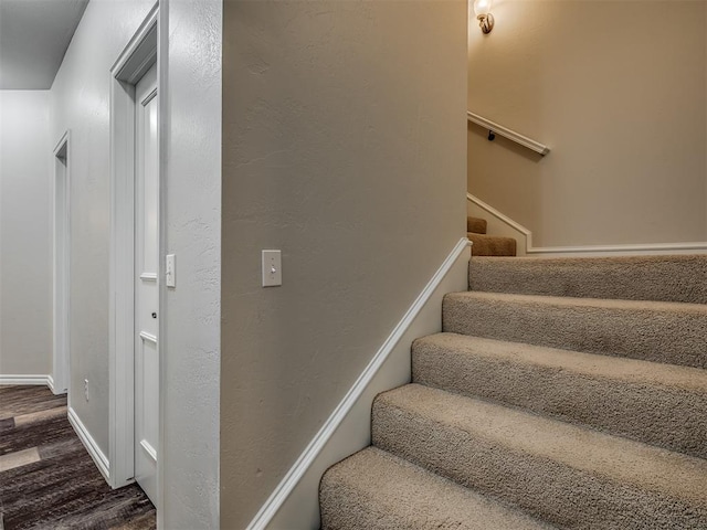 staircase featuring baseboards and wood finished floors