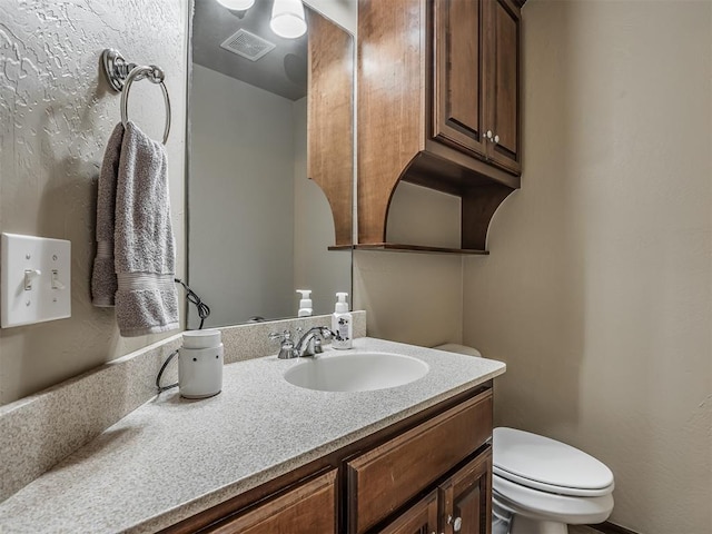 half bath featuring toilet, vanity, and visible vents