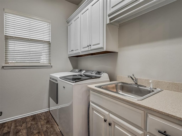 clothes washing area with dark wood-style floors, washer and clothes dryer, cabinet space, a sink, and baseboards