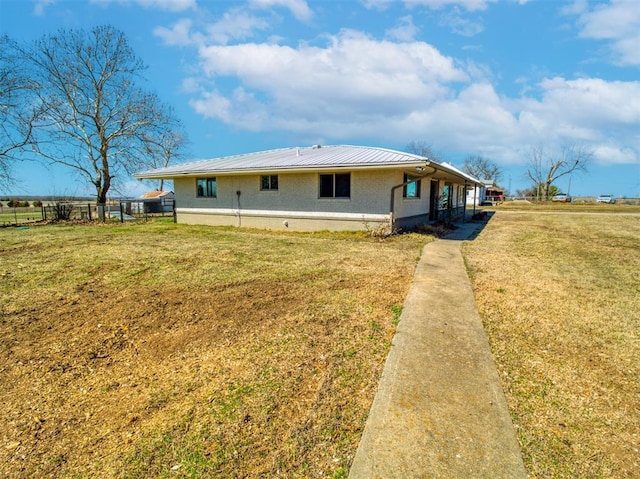 back of house with metal roof, a lawn, and fence