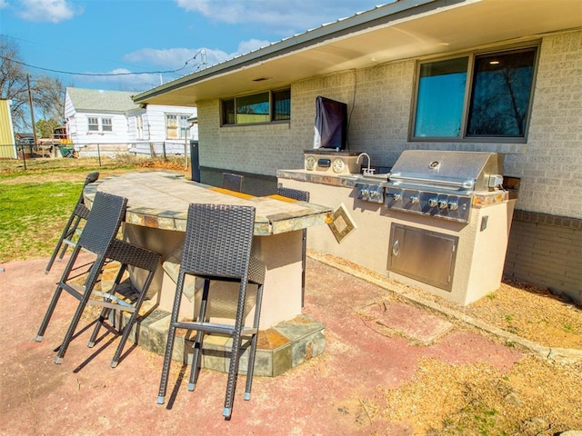 view of patio / terrace with area for grilling, a sink, fence, outdoor dry bar, and exterior kitchen