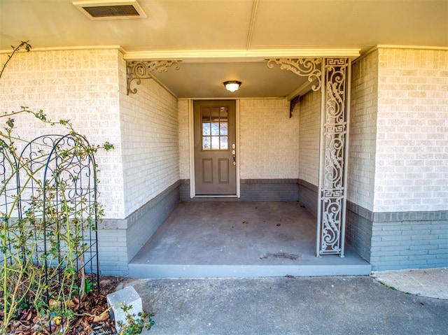 doorway to property with visible vents and brick siding