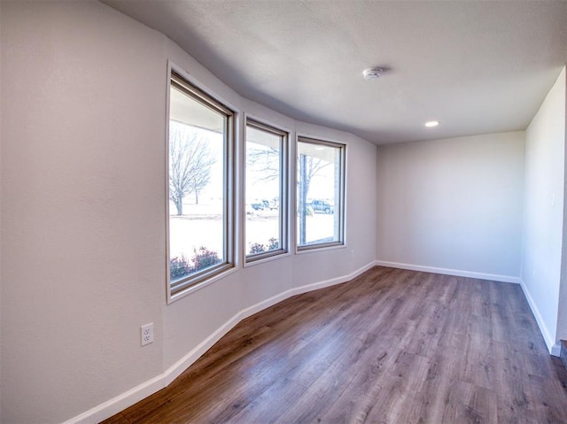 unfurnished room featuring baseboards and dark wood finished floors