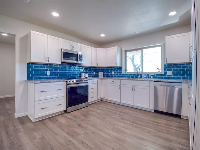 kitchen with light wood-style flooring, white cabinetry, stainless steel appliances, and a sink