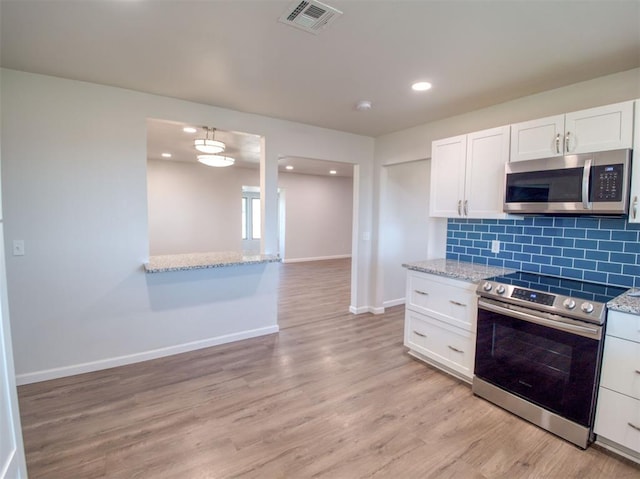 kitchen featuring appliances with stainless steel finishes, white cabinetry, visible vents, and tasteful backsplash