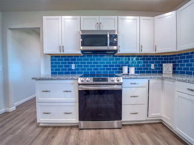 kitchen with light wood finished floors, appliances with stainless steel finishes, backsplash, and light stone counters