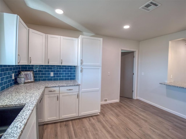 kitchen with recessed lighting, visible vents, white cabinets, light wood-type flooring, and backsplash