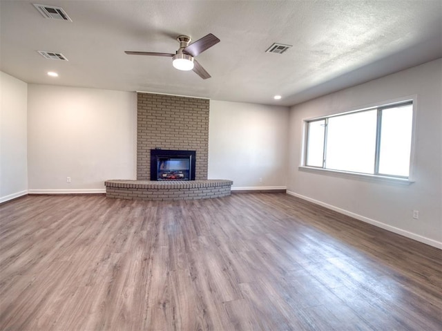 unfurnished living room featuring visible vents, a fireplace, and wood finished floors