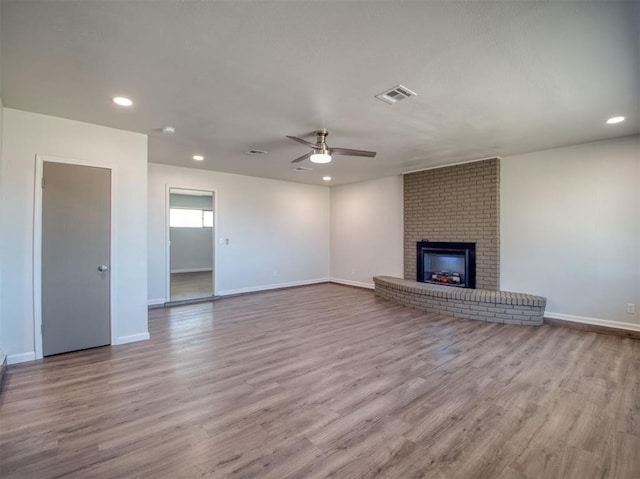 unfurnished living room featuring visible vents, a ceiling fan, wood finished floors, a brick fireplace, and recessed lighting