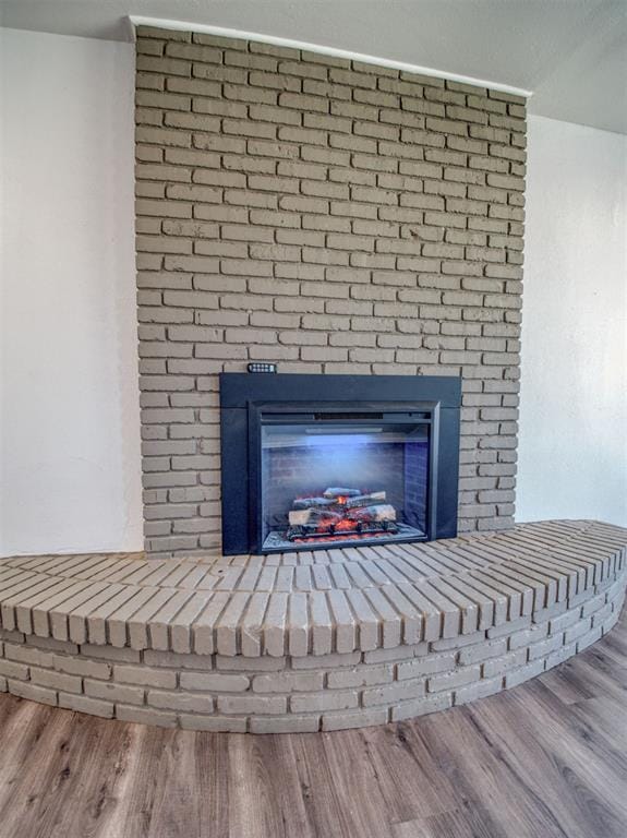 details with a brick fireplace and wood finished floors