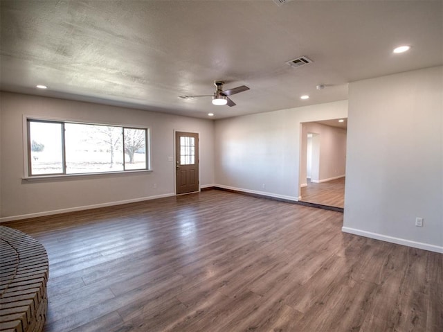 interior space with dark wood-type flooring, visible vents, and baseboards