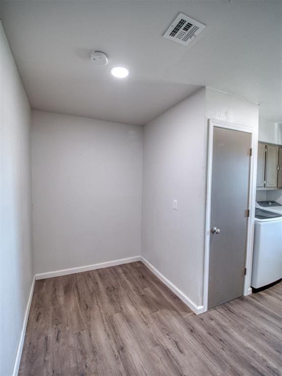 spare room with baseboards, visible vents, washer / clothes dryer, and wood finished floors