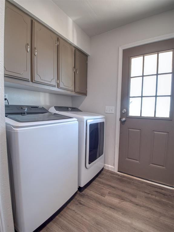 washroom with cabinet space, baseboards, washer and dryer, and wood finished floors