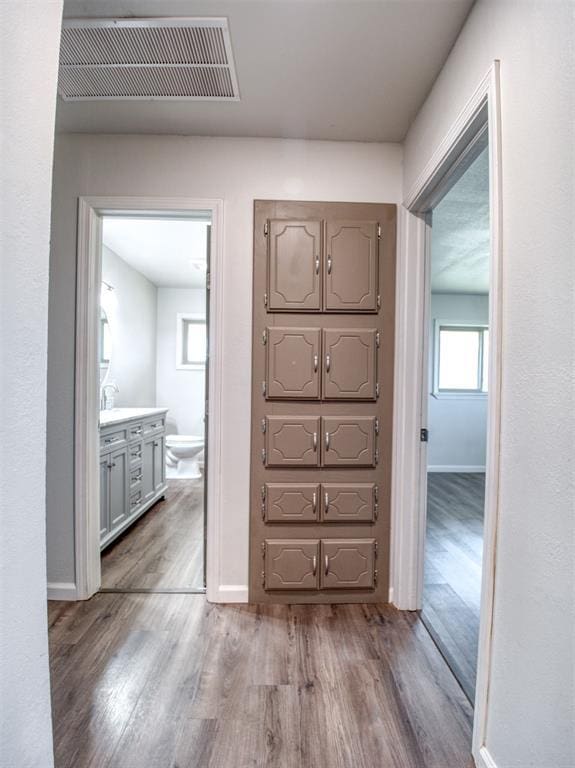 hall with baseboards, visible vents, and wood finished floors